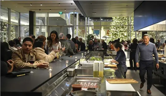  ?? PHOTOS BY JOSE CARLOS FAJARDO — STAFF PHOTOGRAPH­ER ?? General manager Bobby Quintong, right, walks through the kitchen during an opening party held at The Slanted Door at City Center Bishop Ranch in San Ramon. It’s the second location for Charles Phan’s acclaimed Vietnamese restaurant.