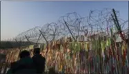  ?? LEE JIN-MAN — THE ASSOCIATED PRESS ?? Visitors walk by the wire fence decorated with ribbons carrying messages to wish for the reunificat­ion of the two Koreas at the Imjingak Pavilion in Paju, South Korea, Thursday.