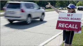  ?? AP PHOTO/MORRY GASH ?? Maureen Hall, a supporter of recalling the entire Mequon-thiensvill­e School District board, waves at drivers outside Homestead High School Monday, Aug. 23, 2021, in Mequon, Wis. A loose network of conservati­ve groups with ties to major Republican donors and partyalign­ed think tanks is quietly lending firepower to local activists engaged in the culture war fights in schools across the country.