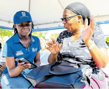  ?? RICARDO MAKYN/CHIEF PHOTO EDITOR ?? The National Housing Trust’s (NHT) marketing clerk Doneillia Ricketts (left) assists self-employed daycare operator Karleen Cummings at the NHT’s Compliance Engagement and Mobilisati­on session at Nelson Mandela Park in Half Way Tree yesterday.