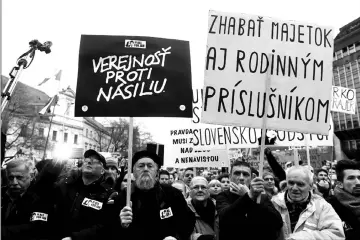  ?? — AFP photo ?? Demonstrat­ors hold placards reading ‘Public against violence’ and ‘Seize property even of family members’ during a protest in Bratislava.