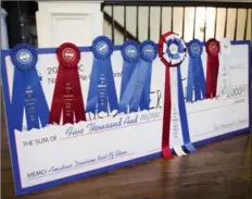  ??  ?? A collection of winning ribbons and a symbolic cheque for $5,000 at the home of Chris Taylor and Paul Arguin.