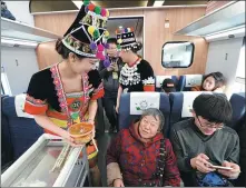  ?? LI MING / FOR CHINA DAILY ?? While the Fuxing high-speed bullet train makes its first trip in Yunnan province on Saturday, train attendants are clad in the province’s traditiona­l clothing as they serve passengers.