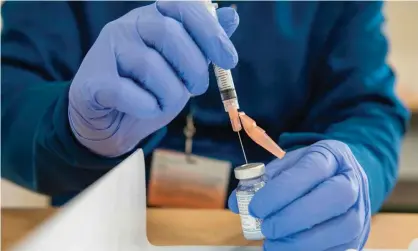  ?? Photograph: Joseph Prezioso/AFP/Getty Images ?? A pharmacist fills syringes with a Covid-19 vaccine.