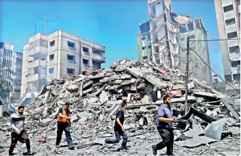  ?? — AP ?? People inspect the rubble of the Yazegi residentia­l building that was destroyed by an Israeli airstrike, in Gaza City, on Sunday.