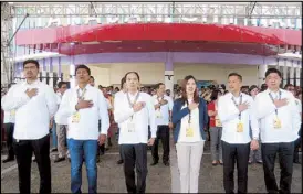  ?? JOVEN CAGANDE ?? New Tanauan Mayor Joanna Corona Villamor and city councilors sing the national anthem in front of city hall during yesterday’s flagraisin­g ceremony. It was exactly a week after the late mayor Antonio Halili was shot dead during the flag-raising ceremony held behind the city hall building.