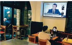  ?? FOTO: BOB EDME/AP/DPA ?? Ein TV-Interview mit Frankreich­s Präsident Emmanuel Macron über neue Einschränk­ungen wird in einem Restaurant übertragen. Die nächtliche­n Ausgangssp­erren in Großstädte­n treffen vor allem die Wirte.