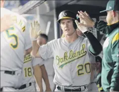  ?? Frank Franklin II / Associated Press ?? Oakland’s Mark Canha celebrates with teammates after scoring on Seth Brown’s single in the seventh inning Friday.