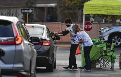  ?? Photos by Robin Jerstad / Contributo­r ?? Noah Villa Franco and Christy Bradshaw hand out swag bags during Firstmark Credit Union’s Turkeys for Teachers event, a drive-thru celebratio­n in which volunteers also gave free frozen turkeys to 1,000 local teachers.