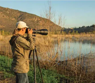  ??  ?? A photograph­er uses a long camera lens to get closeups of wildlife.