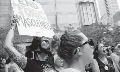  ?? ABEL URIBE/CHICAGO TRIBUNE ?? Rachel Branham of Boston, with mask, holds a sign that reads “End Toxic Masculinit­y” during “SlutWalk Chicago” in 2016.