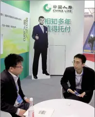  ?? WANG JING / FOR CHINA DAILY ?? Employees of China Life Insurance Co chat at an internatio­nal finance expo in Beijing.