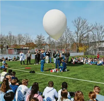  ?? Foto: Thorsten Jordan ?? Schülerinn­en und Schüler der P-Seminare Physik und Chemie lassen am Sportplatz des DZG in Landsberg einen Stratosphä­renballon steigen. Die halbe Schule schaut dabei zu.
