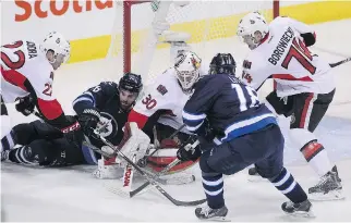  ??   MARIANNE HELM/GETTY IMAGES ?? Andrew Ladd of the Winnipeg Jets battles for the puck with Andrew Hammond of the Ottawa Senators in thirdperio­d action in an NHL game at the MTS Centre on Wednesday in Winnipeg.