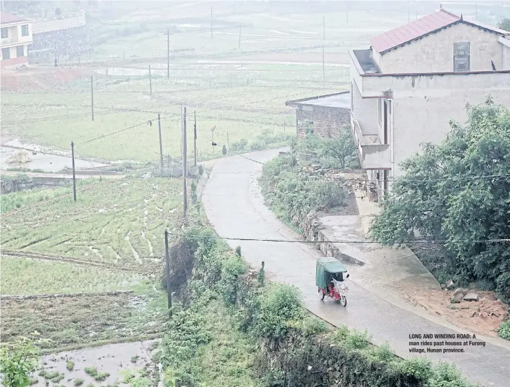  ??  ?? ‘NO FUTURE’: Farmer Liu Deke, 73, and his wife thresh rapeseed in their village. LONG AND WINDING ROAD: A man rides past houses at Furong village, Hunan province.