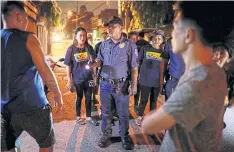  ??  ?? A policeman reprimands men for drinking in public, while accompanyi­ng volunteer patrollers in Pateros.