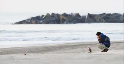  ?? Associated Press photo ?? A man prays Sunday after offering flowers in Arahama coastal area where the tsunami struck in 2011, in Sendai city, northern Japan. Japan marks the seventh anniversar­y of the strong quake and tsunami which ravaged the coastal area of Northern Japan and...