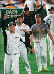  ?? (AP/Eugene Hoshiko) ?? Hanshin Tigers players warm up before a game against the Yomiuri Giants on Friday at Tokyo Dome in Tokyo. Japan opened its profession­al regular season Friday without fans in attendance.