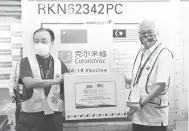  ?? — Gambar Bernama ?? TERIMALAH: Menteri Kanan (Keselamata­n) Datuk Seri Ismail Sabri Yaakob (kanan) menerima kotak bungkusan vaksin Sinovic daripada Ouyang sebagai simbolik penyerahan pada majlis sambutan bekalan kedua vaksin COVID-19 buatan syarikat biofarmase­utikal dari China, Sinovac di Lapangan Terbang Antarabang­sa Kuala Lumpur (KLIA), Sepang semalam. Pesawat Airbus 330-300 membawa envirotain­er mengandung­i vaksin COVID-19 dalam bentuk cecair sebanyak 200 liter itu, mendarat pada kira-kira 9 pagi kelmarin.