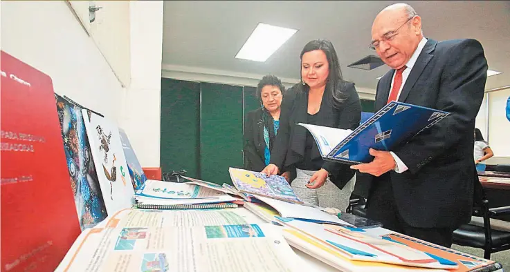  ??  ?? Donación. El ministro de Educación, Carlos Canjura; la directora nacional de Educación de Jóvenes y Adultos, Angélica Paniagua; y Claudia Ramírez, de LA PRENSA GRÁFICA, observan parte del donativo entregado al MINED y a sus círculos de alfabetiza­ción.