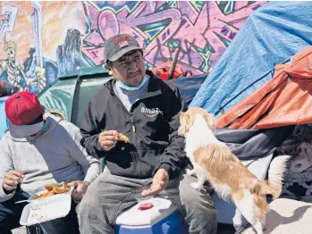  ?? SETHWENIG/AP ?? Alfredo Martinez, right, and Sotero Cirilo eat lunch in front of tents where they have been living in the Queens borough of New York. According to a NewYork City agency, 60% of unauthoriz­ed workers have already lost their jobs.