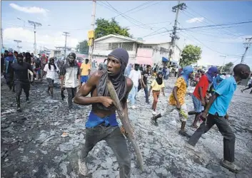  ?? Odelyn Joseph Associated Press ?? A MAN carries a piece of wood as though it were a weapon in Port-au-Prince, Haiti, during a protest in October demanding the resignatio­n of Prime Minister Ariel Henry, who has failed to hold general elections.