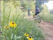  ?? NWA Democrat-Gazette/FLIP PUTTHOFF ?? Riders take off on one of several mountain bike trails that join the hard-surface path at Coler Park and Applegate trails in Bentonvill­e.
