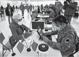  ?? ANTONIO PEREZ/CHICAGO TRIBUNE ?? Jack Alberts gives his informatio­n to a member of the Illinois National Guard before receiving his vaccinatio­n March 5 in Des Plaines.