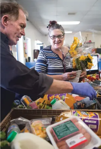  ??  ?? ABOVE: Bienvenido­s Outreach volunteer James Leonard helps put together a food basket as Elizabeth Romero picks one up. Low-income families can apply to receive up to two food baskets a month. The items are collected from grocery stores and community donations and given to recipients.