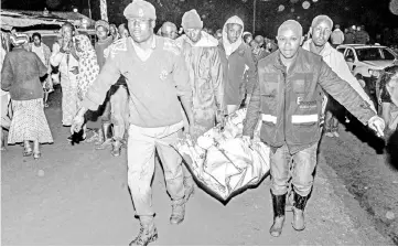  ?? — AFP photo ?? People carry a victim’s body from a residentia­l area after the Patel dam burst its bank at Solai.