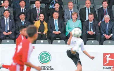  ?? WANG YE / XINHUA ?? President Xi Jinping, German Chancellor Angela Merkel and Xi’s wife, Peng Liyuan, watch an exhibition soccer game between youths from the two countries at Berlin’s Olympic Stadium on Wednesday. Chinese players are attending a camp in Germany as part of...