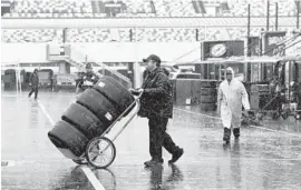  ?? CHUCK BURTON/ASSOCIATED PRESS ?? A crew member hauls tires Saturday through the NASCAR Xfinity garage at Charlotte Motor Speedway. Racing was postponed to today because of Hurricane Matthew.