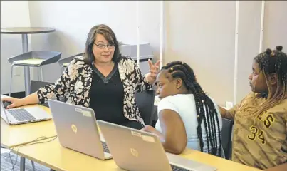  ?? Lake Fong/Post-Gazette ?? Connie Capiotis, left, founder of Digital Bridges, works with Da'kiyan Jackson Turner, center, and Kaelyn Benton, both 10, of Hazelwood at the library in Hazelwood.