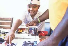  ??  ?? Antonio Braxton Jr. and his father flip through a photo album of their time following Memphis sports.