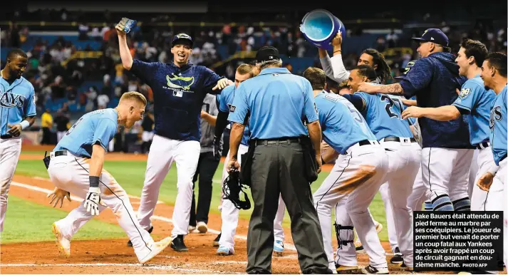  ?? PHOTO AFP ?? Jake Bauers était attendu de pied ferme au marbre par ses coéquipier­s. Le joueur de premier but venait de porter un coup fatal aux Yankees après avoir frappé un coup de circuit gagnant en douzième manche.