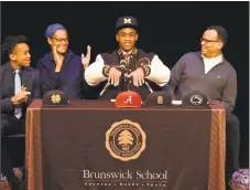  ?? Tyler Sizemore / Hearst Connecticu­t Media ?? Brunswick receiver Cornelius Johnson, of Greenwich, announces his commitment to play football at the University of Michigan beside his parents Cassandra Tribble, M.D., and Claude Johnson.