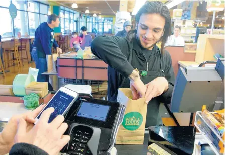  ?? MARLA BROSE/JOURNAL ?? Whole Foods is among the national chains that accept Apple Pay, including at its two Albuquerqu­e stores. Checker Rumaldo Armijo is pictured bagging groceries following an Apple Pay transactio­n at the Whole Foods on Wyoming NE.