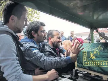  ?? Cagdas Erdogan Associated Press ?? THE BROTHER of Sarigul Tuylu, 35, a mother of two who was killed in the bombings in Ankara, cries over her coffin in Istanbul. Saturday’s attack took place at the site of a peace rally in the Turkish capital.