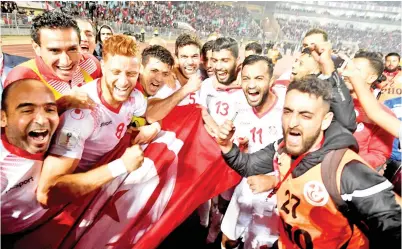  ??  ?? PARA pemain Tunisia memegang bendera kebangsaaa­n meraikan kejayaan mereka layak ke Piala Dunia 2018. -Gambar AFP