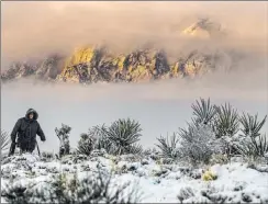 ?? L.E. Baskow Las Vegas Review-journal @Left_eye_images ?? Sylvia Hinojosa hikes up to the overlook as the clouds break on a snowy Tuesday in the Red Rock National Conservati­on Area.
