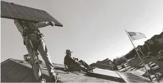  ?? SolarCity ?? Workers install a SolarCity rooftop solar system at a home in the Dallas area.