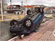  ??  ?? KERETA terbalik, manakala bumbung bangunan ditiup angin kencang di Saint Martin. - Daily Mail