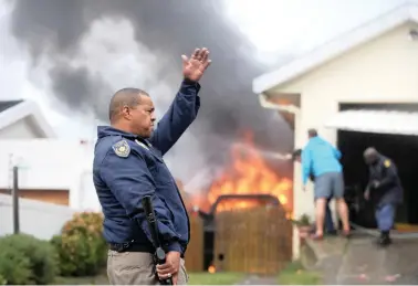  ?? PICTURE: ARMAND HOUGH/AFRICAN NEWS AGENCY (ANA) ?? TEMPERS FLARE: Authoritie­s try to extinguish a car that was set alight by protesters yesterday as residents of Hangberg in Hout Bay took to the streets after it was alleged a fisherman was shot by police.