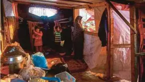  ?? AFP PIX ?? (Top) Hani al-Laham, a Palestinia­n government employee, sweeping the street outside a coffee kiosk in Gaza City recently. (Bottom) Laham’s wife, Noor, with her children in their home in Gaza City.