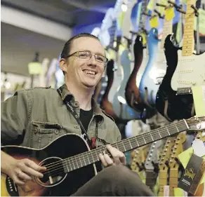  ?? IAN KUCERAK ?? Scott McCarthy, an Axe Music guitar sales representa­tive, plays a Seagull guitar in the company’s Wayne Gretzky Drive location on Saturday. He’s found interest in guitars has waned recently.