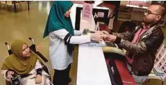  ??  ?? Siti Nor Aishah dibantu rakan ketika proses peminjaman buku di perpustaka­an MSU.