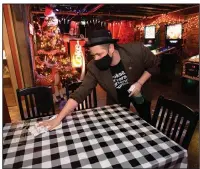  ?? (NWA Democrat-Gazette/Andy Shupe) ?? Bo Counts, owner of Pinpoint, wipes down tables with disinfecta­nt on Thursday as he and staff members prepare to open the bar on Block Avenue in Fayettevil­le. Counts is among the bar owners challengin­g the state’s 11 p.m. curfew on alcohol sales.