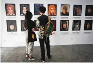  ??  ?? Anime fan Kullanit Assawawong­kasem (left) and her boyfriend looking at oil portraits of deceased anime characters.