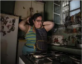  ?? PHOTOS BY RAMON ESPINOSA — THE ASSOCIATED PRESS ?? Yuliet Colon puts on her apron as she prepares to cook a dish in her kitchen in Havana, Cuba, on April 2.