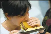  ??  ?? French food blogger Ghislaine Challamel takes a bite of an Impossible Burger burger during a presentati­on in Redwood City. The company recently opened a production facility in Oakland.